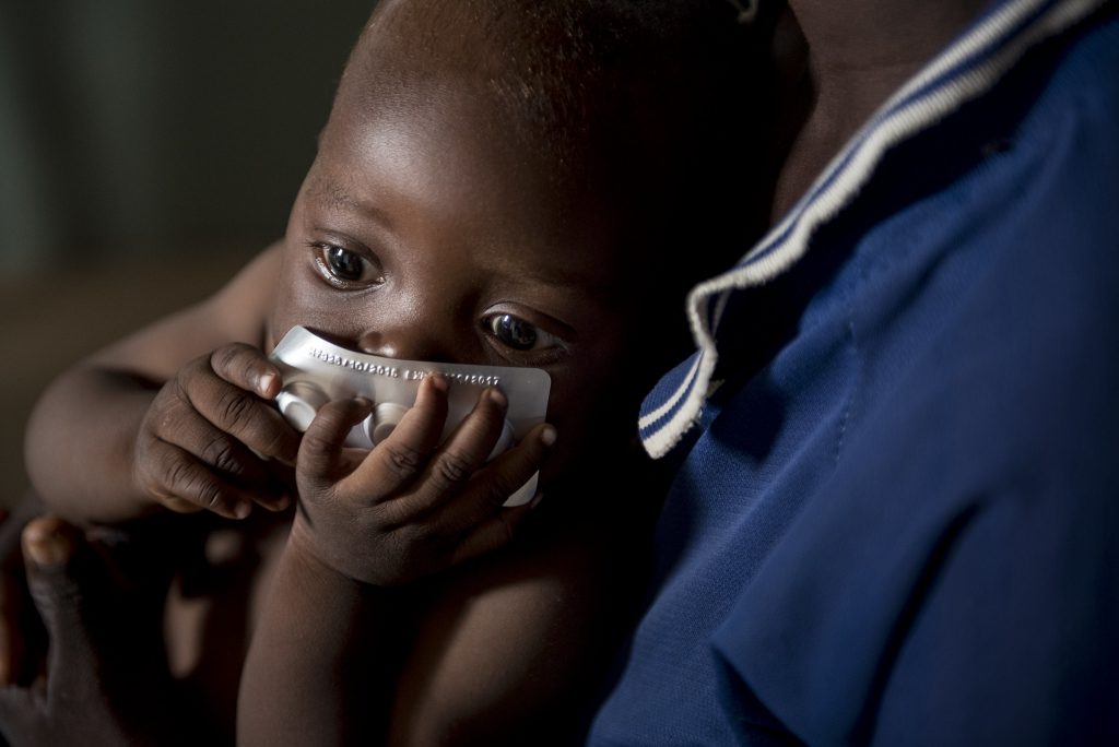 Baby holding malaria medication.