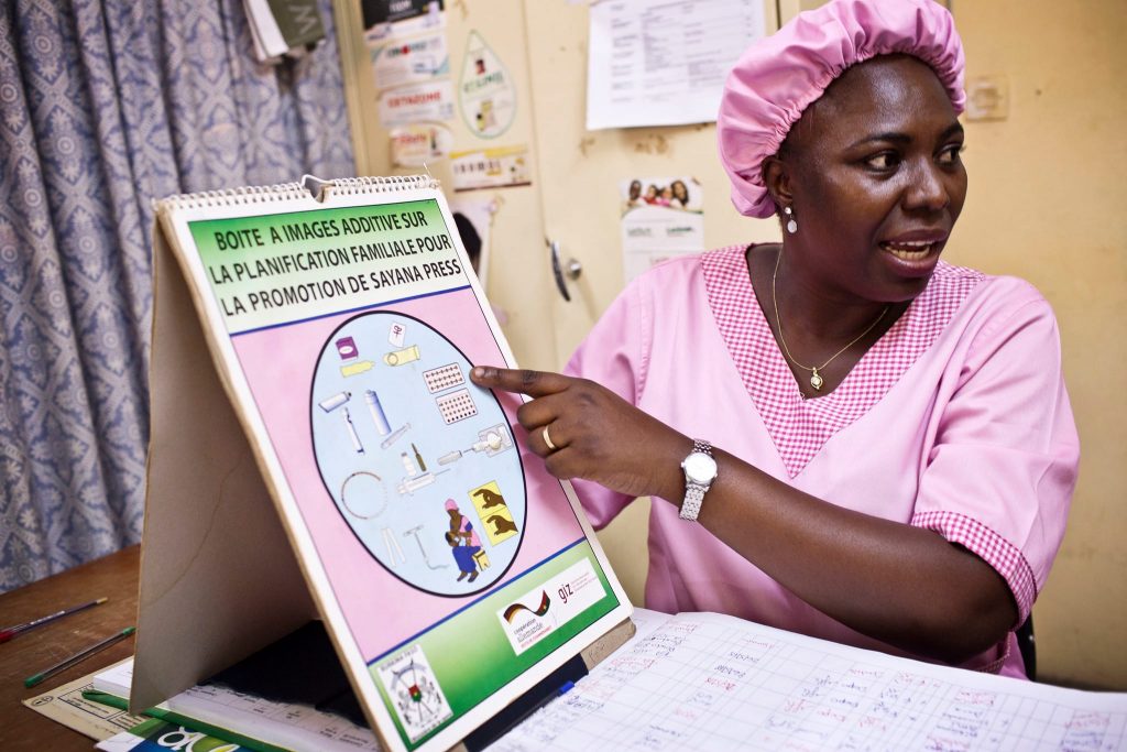 A midwife pointing to a chart showing different types of family planning methods