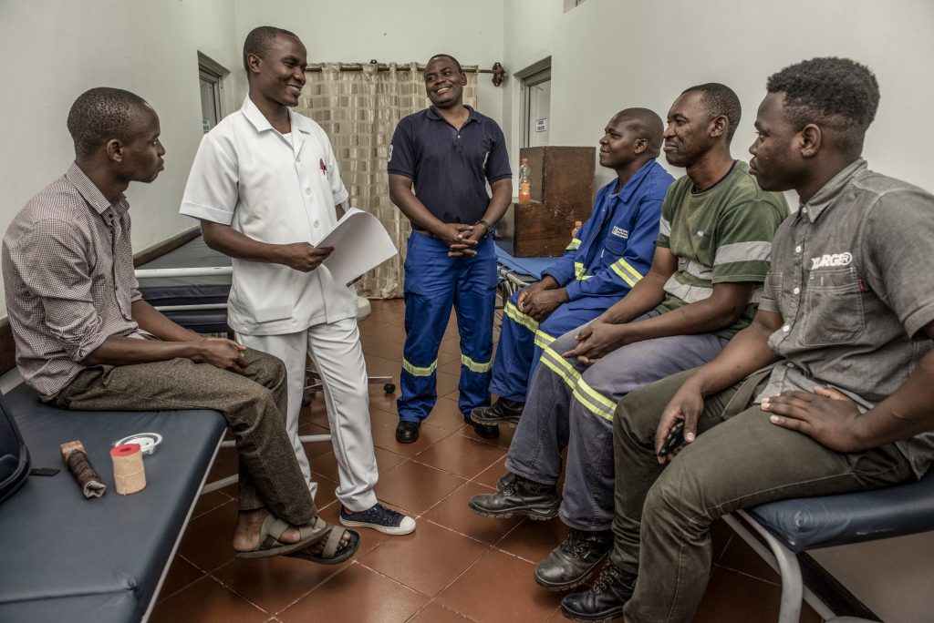 Male nurse speaking with a group of men at a health clinic.